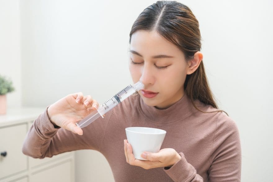 Persona realizando un lavado nasal con solución salina para aliviar la congestión
